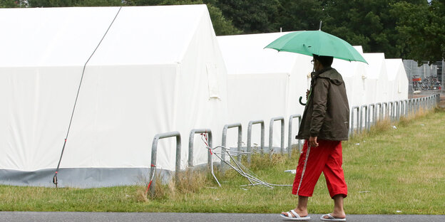 Ein Mann geht an Zeltunterkünften für Flüchtlinge vorbei
