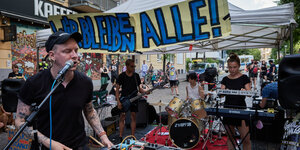 Die vier Mitglieder der Band ÖPNV spielen vor einem Banner mit der Auffschrift "Wir Bleben Alle!"