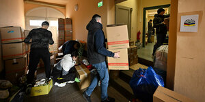 Helfer tragen in Erfurt Kisten mit Spenden für die Ukraine in ein Haus