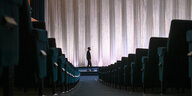 Ein Mann steht vor der Leinwand eines leeren Kinos