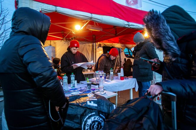 ein beleuchteter Stand vor dem Menschen in warmen Jacken warten