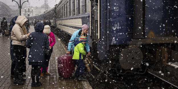 Mehrere Menschen steigen bei Schnee in einen Zug