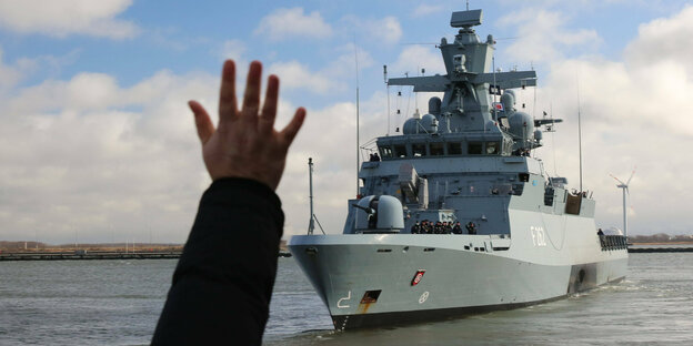 Eine Hand winkt einem Schiff der Marine.