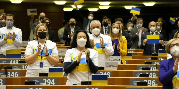 Mitgleider des EU-Parlaments tragen T-Shirts mitder ukrainischen Flagge und applaudieren
