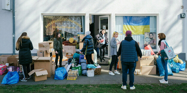 Menschen geben Spenden vor einer Sammelstelle ab Menschen geben Spenden vor einer Sammelstelle ab