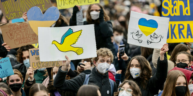 Teil­neh­me­r:in­nen der Fridays-for-Future-Demo halten Plakate in den ukrainischen Farben hoch