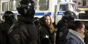 Eine Frau wird von Polizisten festgenommen.