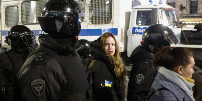 Eine Frau wird von Polizisten festgenommen.