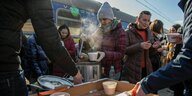 Menschen verteilen Suppe auf einem Bahnsteig