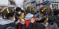 Schüler:innen binden sich Schleifen in den ukrainischen Farben gelb und blau in die Haare