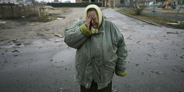 Eine Frau weint vor ihrem zerstörten Haus