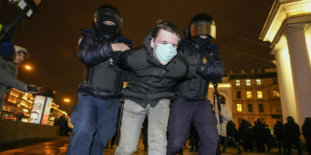 Ein Demonstrant wird rabiat von behelmten Polizisten fesgtenommen
