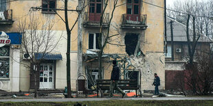 Ein Mann geht an einem Haus mit einem Bombenkrater vorbei