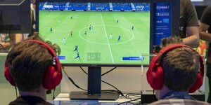 Zwei Kinder zocken an einem Monitor FIFA