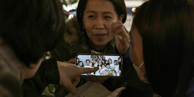 Philippinin mit Familienfoto auf dem Handy