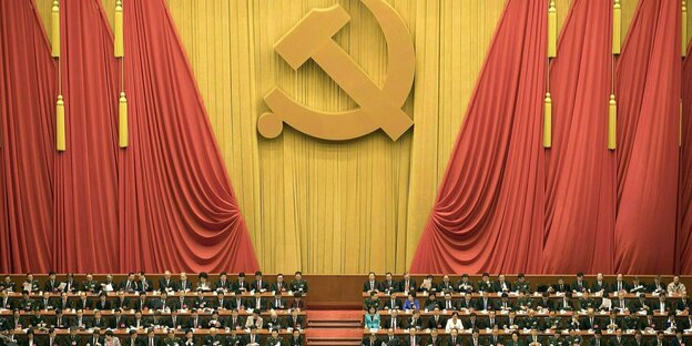 Blick auf den Parteikongress, im Hintergrund ist eine riesige Abbildung von Hammer und Sichel zu sehen