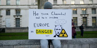 ein Demonstrant trägt ein Schild mit der Aufschrift : " Er hat Tschernobyl eingenommen und er ist wahsinnig. Europa ist in Gefahr."