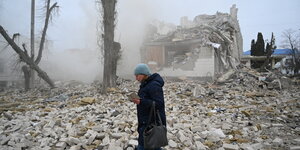 Eine Frau steht in einem Meer von zertrümmerten Häusern
