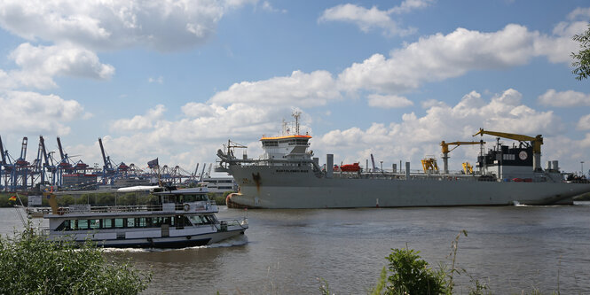 Eein Schiffsbagger auf der Elbe vor Hamburger Hafenkränen