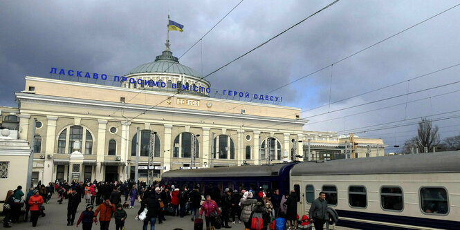 Erwachsene und Kinder stehen auf dem Bahnsteig vor der Abfahrt des Evakuierungszugs Odesa-Lwiw-Rachiw im Bahnhof von Odessa in der Südukraine