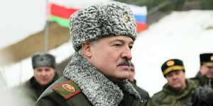 Alexander Lukaschenko, "Präsident" von Belarus, mit Pelzmütze und SOldaten im Hintergrund