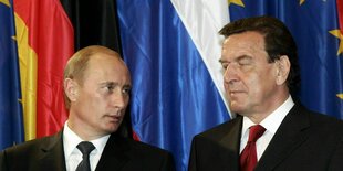 Gerhard Schröder und Wladimir Putin stehen vor einer Deuschland-, Russland- und Europafahne