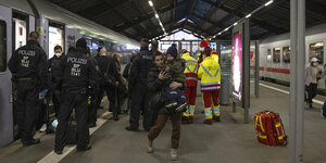 Polizisten und Freiwilige helfen Menschen aus dem Zug