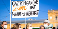 Eine Demonstrantin hält vor dem Hannoverschen Hauptbahnhof ein Schild in die Luft, auf dem steht: Gazpromganove Gerhard hat Hannover Hausverbot