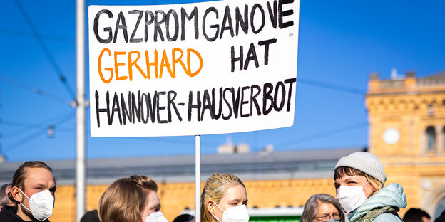 Eine Demonstrantin hält vor dem Hannoverschen Hauptbahnhof ein Schild in die Luft, auf dem steht: Gazpromganove Gerhard hat Hannover Hausverbot
