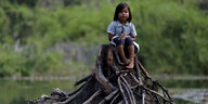 Ein Mädchen sitzt auf einem abgeholzten Baumstumpf