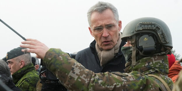 Jens Stoltenberg steht neben einem Soldaten