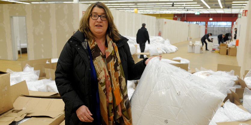 Bremens Sozialsenatorin Anja Stahmann steht in einer Halle und hält ein Kissen