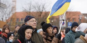 Mehrere Demonstranten und eine Frau mit Ukraine-Fahne