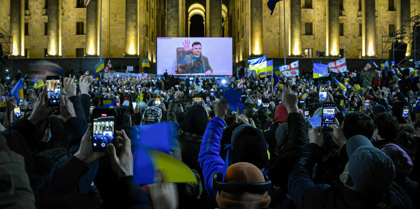 Menschen stehen mit ukrainischen und georgiscgen Flaggen vor dem Parlament in Tiflis