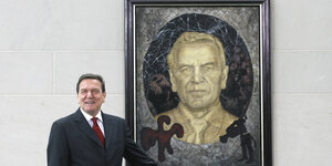 Gerhard Schröder neben einem Porträtbild von ihm.