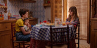 Janis (Penélope Cruz) und Ana (Milena Smit) sitzen mit einem Kind am Frühstückstisch