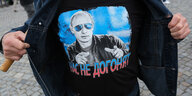 Eine Person zeigt sein Shirt, das mit dem Konterfei Putins bedruckt ist
