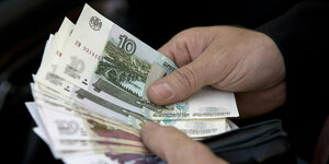 Ein Mann hält russische Rubel-Banknoten in den Händen.