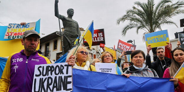 Menschen mit Ukraine-Fahnen und Plakaten auf einer Demo.