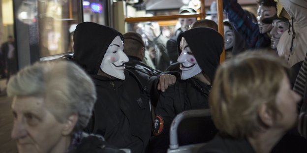 Menschen Bus mit Anonymus-Masken