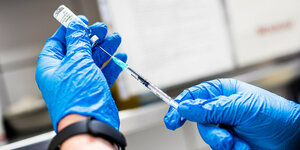 Ein Mitarbeiter des Impfzentrums zieht eine Spritze mit einem Corona-Impfstoff
