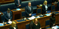 Poltikerinnen und Politiker stehen für eine Schweigeminute im Plenarsaal