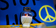eine Kerze steht vor einem Friedenszeichen