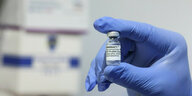 Mitarbeiter hält eine Ampulle eines Impfstoffes in der Hand
