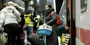 Eine Frau steigt aus dem Zug und hält eine Transportbox für Tiere in der Hand