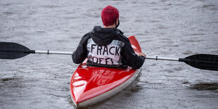 Ein Kanufahrer im Wasser. Auf seinem Rücken steht "Frack off"