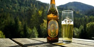 Eine Flasche Bier und ein Bierglas stehen auf einem Tisch in den Bergen