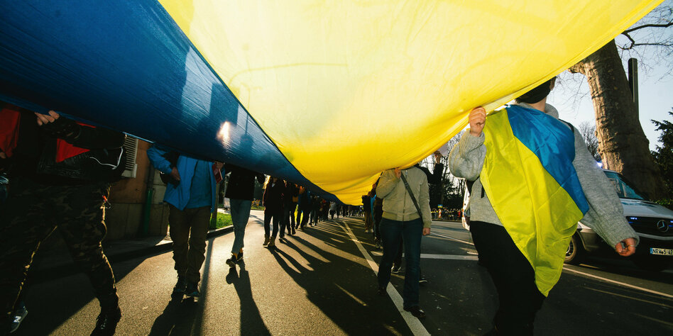 Menschen tragen eine riesige ukrainische Flagge