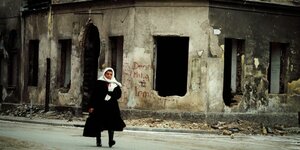 Eine Frau geht durch eine völlig vom Krieg zerstörte Stadt