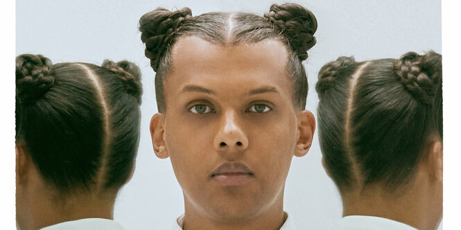 Stromae vor einem Spiegel, der seinen Kopf zweimal spiegelt